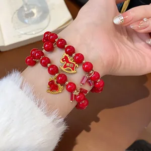 Close-up of elegant red beaded bracelets with gold horse charms on a woman's wrist
