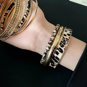 Close-up of stylish leopard print and gold metal bangles set on a female model's wrist