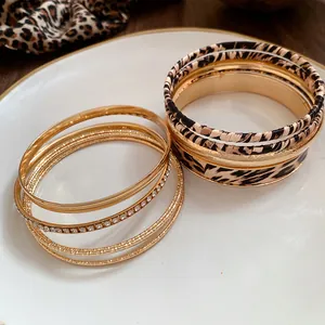 Detailed close-up of leopard print and gold metal bangles set on a white ceramic plate