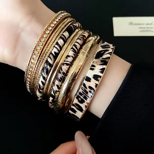 Detail showing texture of leopard print and glossy gold bangles stacked on wrist