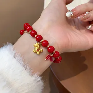 Elegant red beaded bracelet featuring a gold horse charm and red crystals on a wrist.