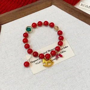 Detailed view of an elegant red beaded bracelet featuring a golden rocking horse charm