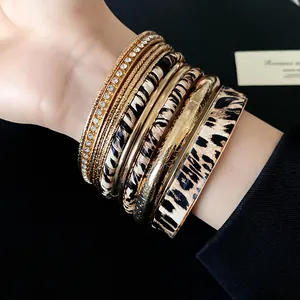 Macro view of multi-layered gold bracelets with leopard print and sparkling rhinestones