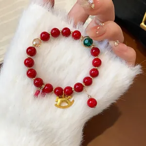 Macro view of red beaded bracelet with golden rocking horse charm on white faux fur