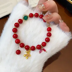 Close-up of a festive red beaded bracelet with golden horse charm on a soft fur sleeve