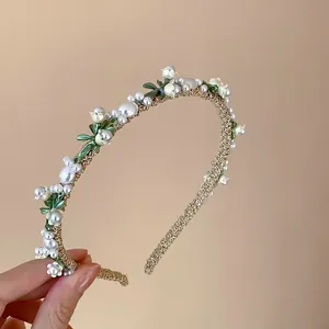 Vue de face d'un élégant serre-tête français en perles de muguet avec tressage doré