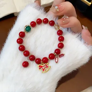 Close-up of a red beaded bracelet with a zodiac horse charm and green accent bead