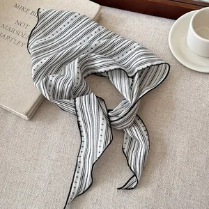 Close-up detail of black and white striped ribbon scarf with delicate stitched edges