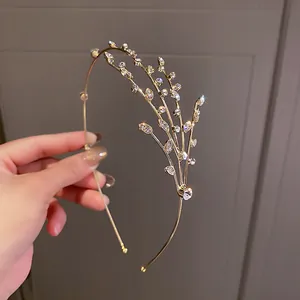 Gros plan d'un serre-tête doré élégant orné d'un motif de branches en strass brillants.