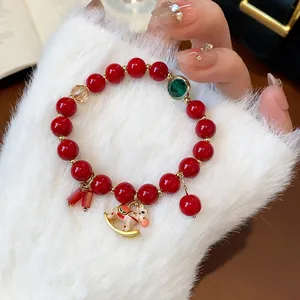 Detailed view of red beaded bracelet featuring a cute golden rocking horse charm