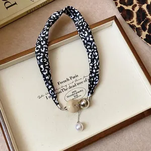 Close-up detail of vintage leopard print fabric necklace with beads and white pearl