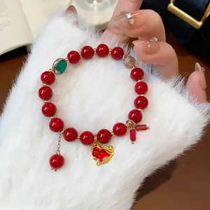 Detail shot of a luxury red beaded bracelet featuring a delicate gold horse charm