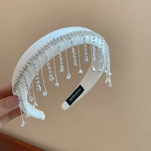 Détail d'un serre-tête blanc élégant avec glands en strass et étiquette Hand Made