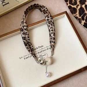 Detailed view of a retro leopard print fabric necklace with a pearl pendant and bead.