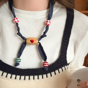 Detailed close-up view of a handmade fabric and wooden heart necklace worn by a model