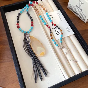 Vintage bohemian beaded necklace featuring a large yellow agate pendant and long leather tassels