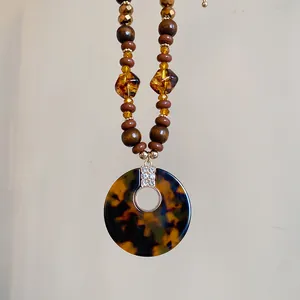 Detail showing vintage wooden beads and leopard pattern pendant with crystals.