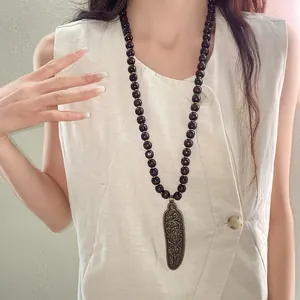 Detailed shot of vintage wood bead necklace with engraved floral bronze pendant