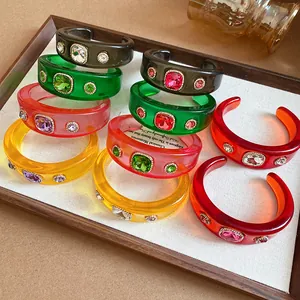 Close-up of colorful resin cuff bracelets with large faceted rhinestones in a tray