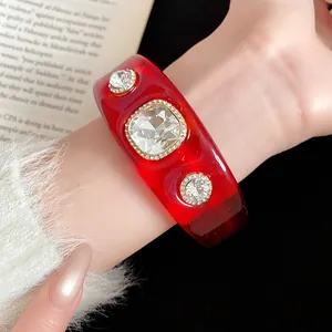 Detail view of a bold red resin cuff bracelet featuring large square and round rhinestones.