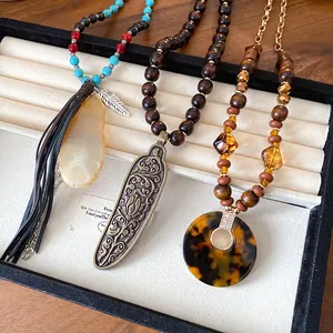 Close-up of bohemian necklaces with wood beads and carved geometric pendants.