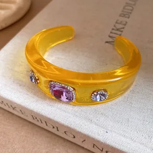 Detailed view of yellow translucent resin cuff bracelet with embedded purple crystals