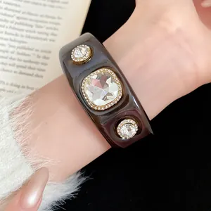 Detailed macro view of a dark resin bangle bracelet featuring large sparkling crystals.