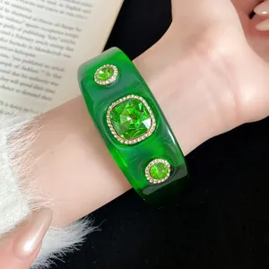 Close-up of green translucent resin bangle featuring large emerald-colored crystals