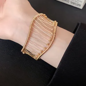 Detailed macro view of a French vintage gold woven hollow grid cuff bracelet on a wrist