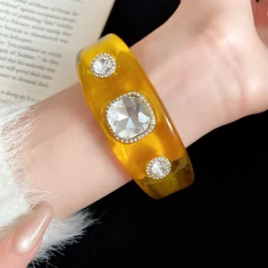 Close-up of amber resin bangle with square and round crystals on a model's wrist