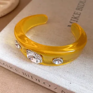 Detailed close-up of a yellow resin cuff bracelet with large sparkling crystal embellishments