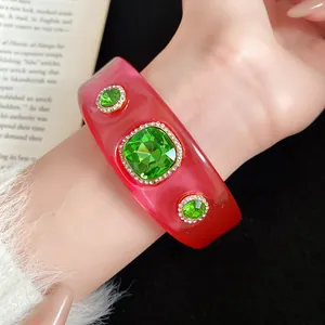 Macro view of a stylish gradient pink resin bangle with sparkling green crystal embellishments