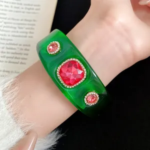 Close-up detail of a green resin bangle with pink faceted stones and rhinestones.