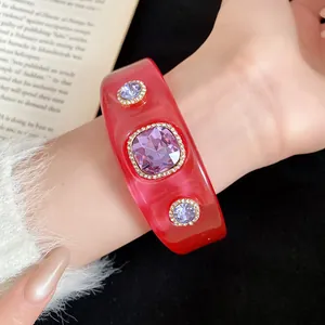 Detailed macro view of a red resin bangle featuring three inlaid purple crystal gemstones.