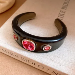 Close-up of black resin cuff bracelet with pink crystal rhinestones on a vintage book