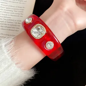 Close-up detail of a red translucent resin bangle featuring sparkling faceted clear crystals