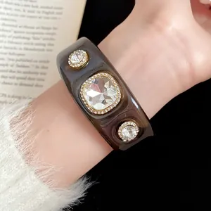 Close-up of large rhinestones on a dark translucent gradient resin cuff bracelet.