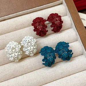Dettaglio di orecchini vintage a forma di C con fiori in bianco, rosso e blu