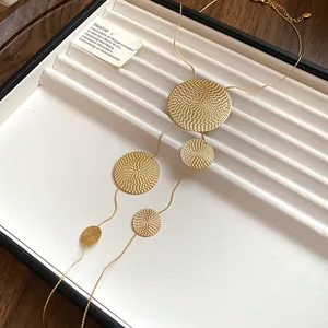 Vue détaillée d'un collier lasso doré avec des pendentifs circulaires en métal texturé