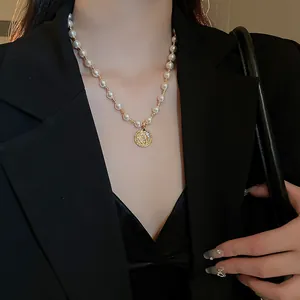 Elegante Perlenkette mit vergoldetem Münzanhänger an einem Model im schwarzen Blazer