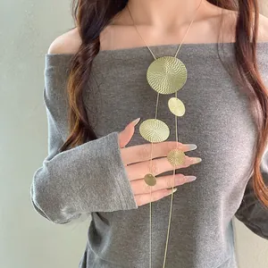 Détail d'un collier à pampilles doré unique avec des disques ronds texturés