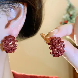 Primo piano di orecchini a lobo vintage bordeaux a forma di C con fiori traforati donna