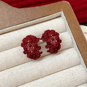Dettaglio degli orecchini a forma di C con piccoli fiori rosso scuro stile vintage
