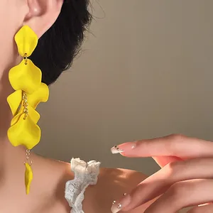 Detailed close-up of vibrant yellow bohemian petal tassel earrings worn by a model
