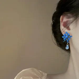 Primo piano di eleganti orecchini a fiore blu con ciondolo a goccia d'acqua sull'orecchio