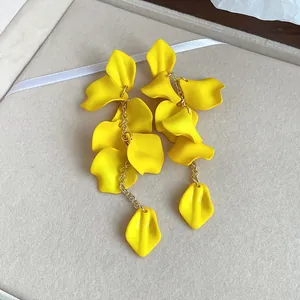 Detail view of vibrant yellow bohemian style petal tassel earrings with a gold chain