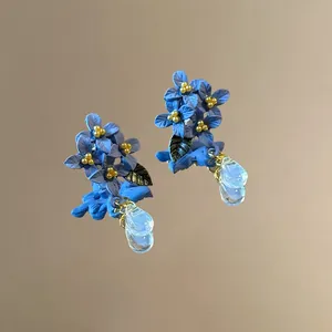Primo piano di orecchini a fiore blu con dettaglio foglia e pendente a goccia