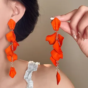 Detail view of vibrant orange Bohemian petal tassel drop earrings with gold chain.