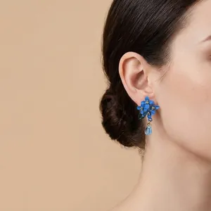 Dettaglio dell'orecchino a fiore blu con foglia e ciondolo a goccia d'acqua sull'orecchio
