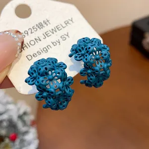 Dettaglio ravvicinato di orecchini a cerchio floreali a C blu opaco con ago S925